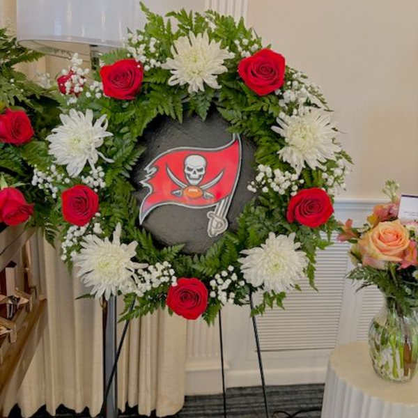 Floral wreath with red roses and white chrysanthemums around a sports logo