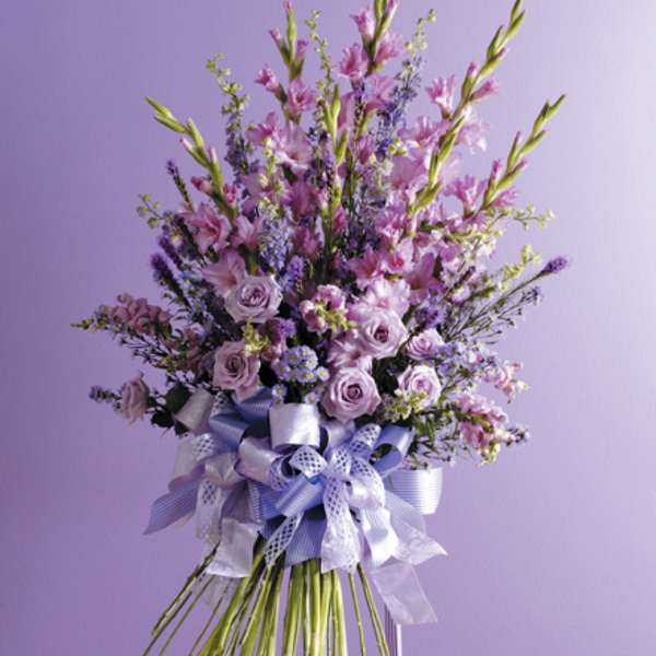 Tall lavender floral spray on an easel with a large ribbon bow