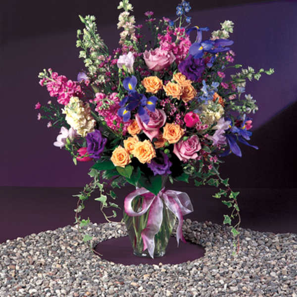 Tall mixed bouquet in a glass vase with a pink ribbon