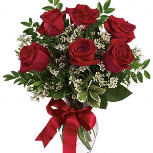 Red roses in a glass vase with a red ribbon