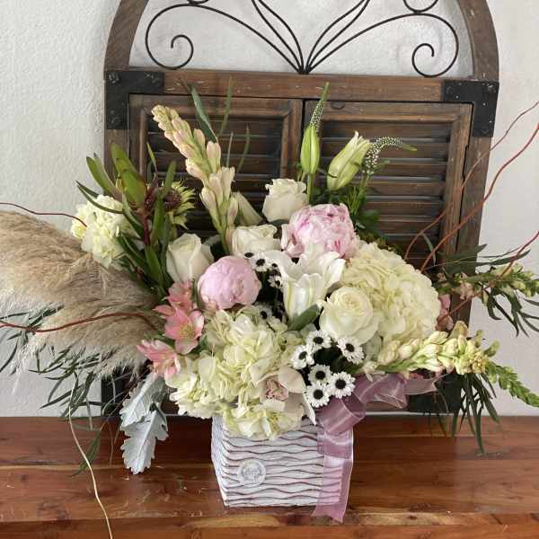 Mixed bouquet in a striped square container with pink ribbon