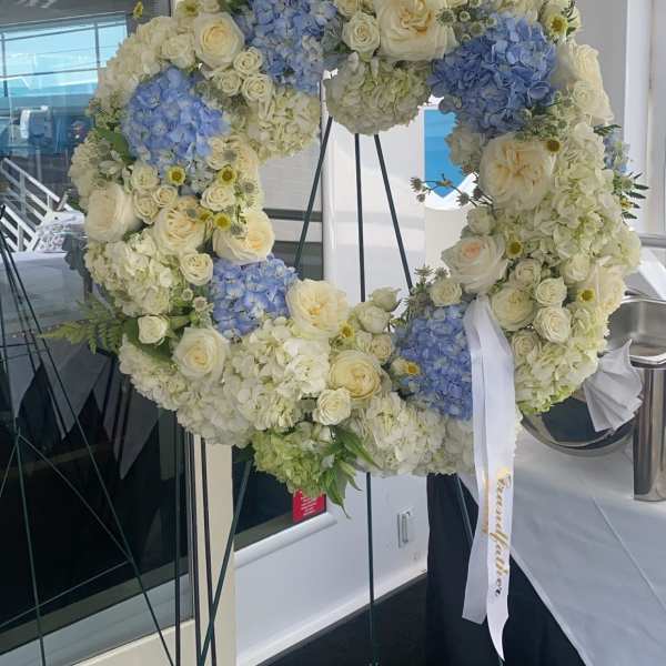 Large floral wreath of white and blue blooms on a stand