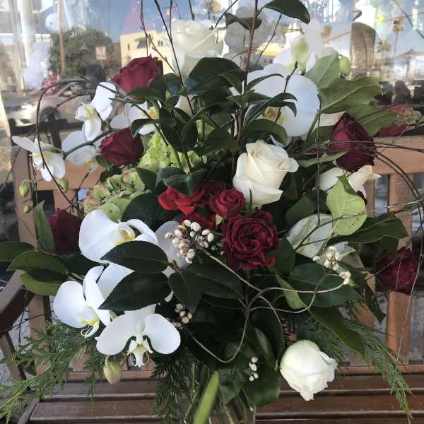 Bouquet of red and white roses with white orchids in a clear glass vase