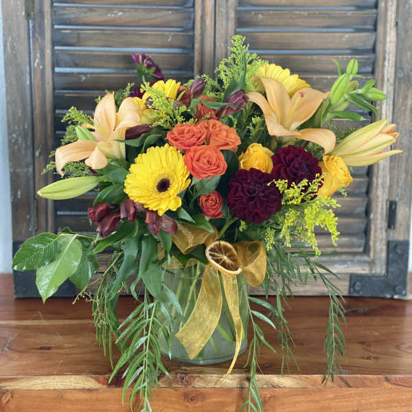 Mixed bouquet in a glass vase with lilies, roses, and yellow daisies