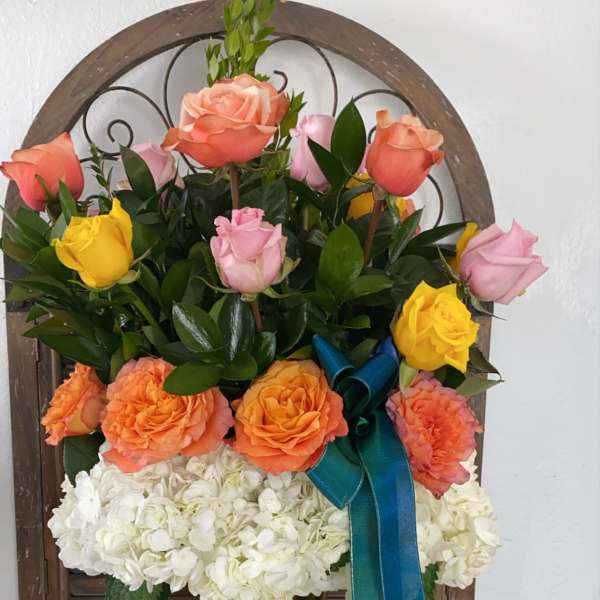 Mixed roses and white hydrangeas in a glass vase with a blue ribbon