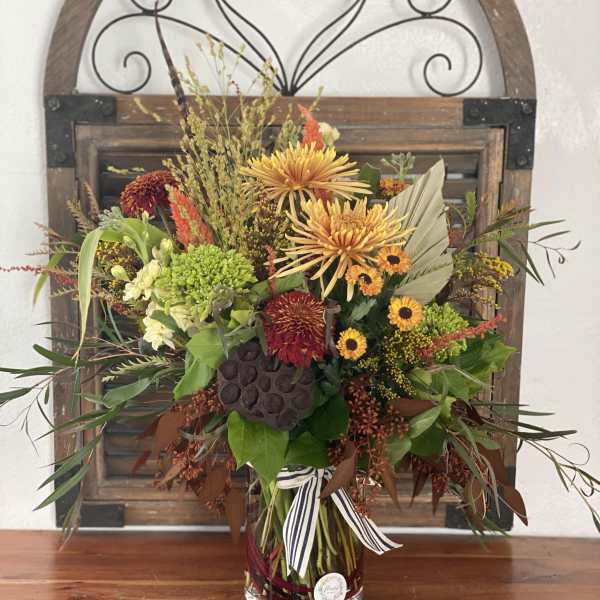 Autumn bouquet of mixed flowers in a glass vase with a striped ribbon