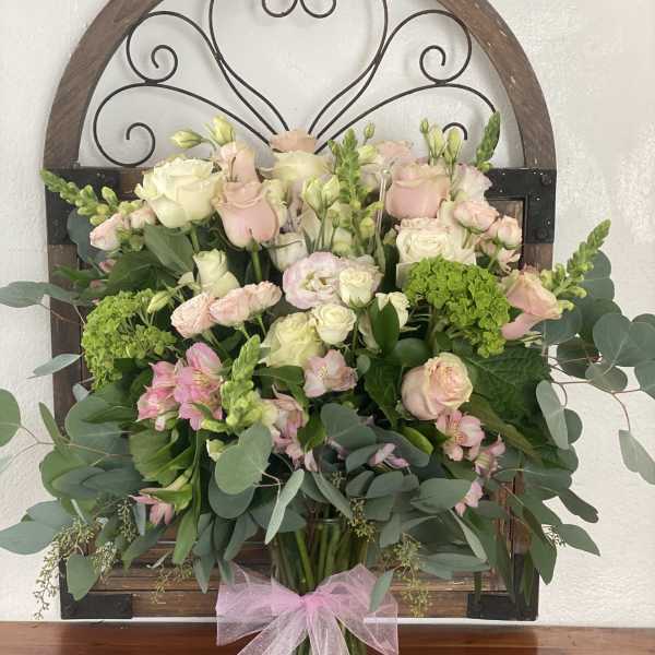 Bouquet of pink and white roses with greenery in a glass vase