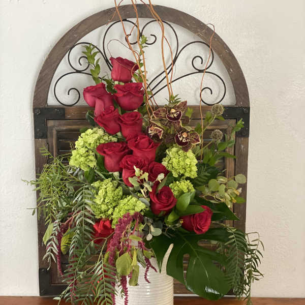 Tall arrangement of red roses and green hydrangeas in a white vase