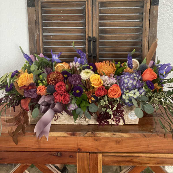 Colorful mixed flower arrangement in a rustic wooden box with a ribbon