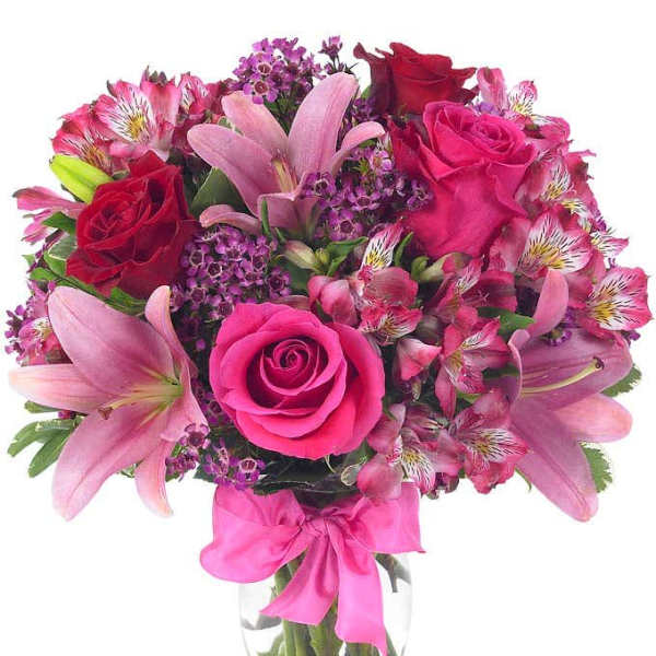 Pink and red mixed bouquet in a clear glass vase with a pink ribbon