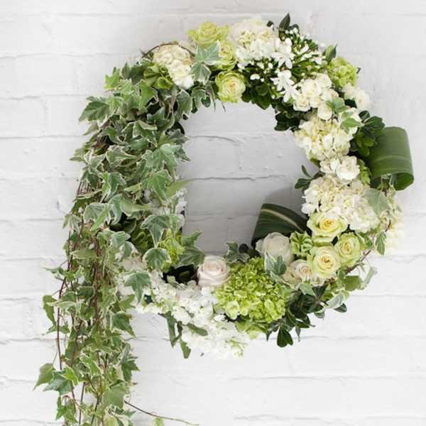 Circular floral wreath with white and green flowers and trailing ivy