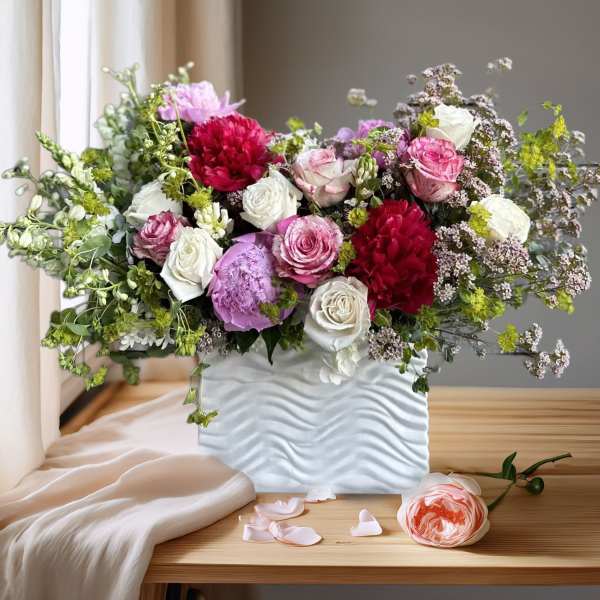 Mixed bouquet of pink, white, and red flowers in a white vase