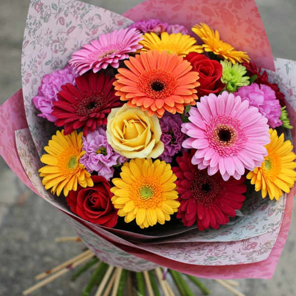 Mixed bouquet of gerbera daisies and roses wrapped in pink paper