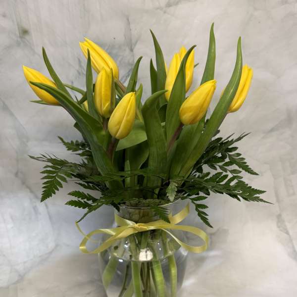 Yellow tulip bouquet in a glass vase with a yellow ribbon