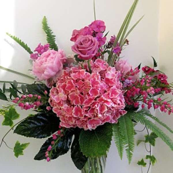 Pink floral arrangement in a clear glass vase with roses and hydrangea