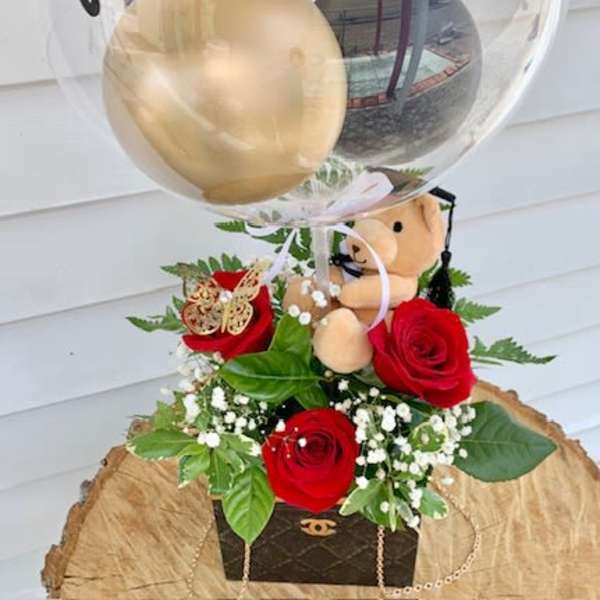 Clear balloon with "Congratulations" over red roses and a teddy bear
