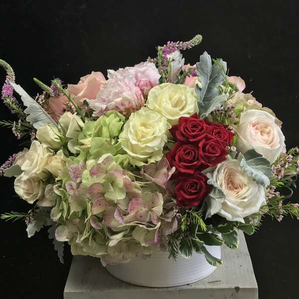 Mixed bouquet of roses and hydrangeas in a white container