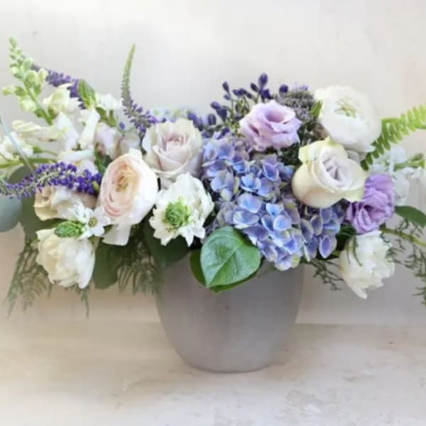 Lavender and white floral arrangement in a gray vase