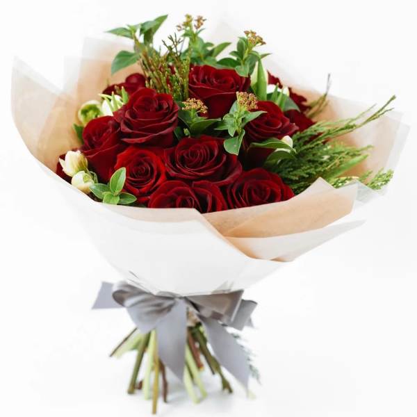 Bouquet of red roses wrapped in white paper with a gray ribbon