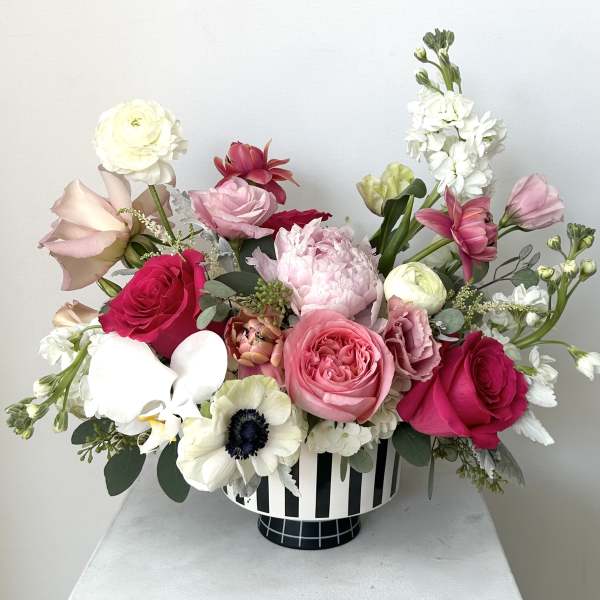 Mixed pink and white flower arrangement in a striped vase