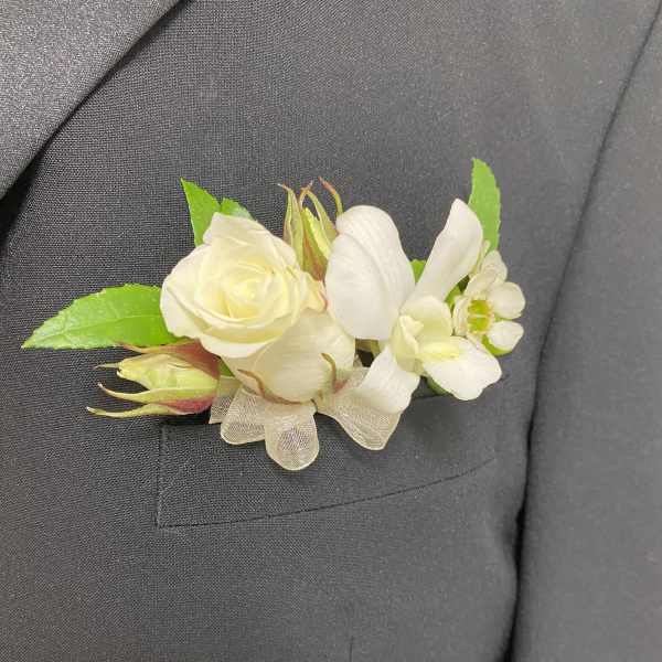 White boutonniere with rose and orchid on a dark suit lapel