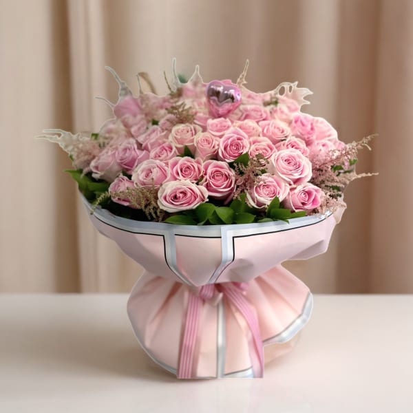 Bouquet of pink roses wrapped in pale pink paper with a ribbon
