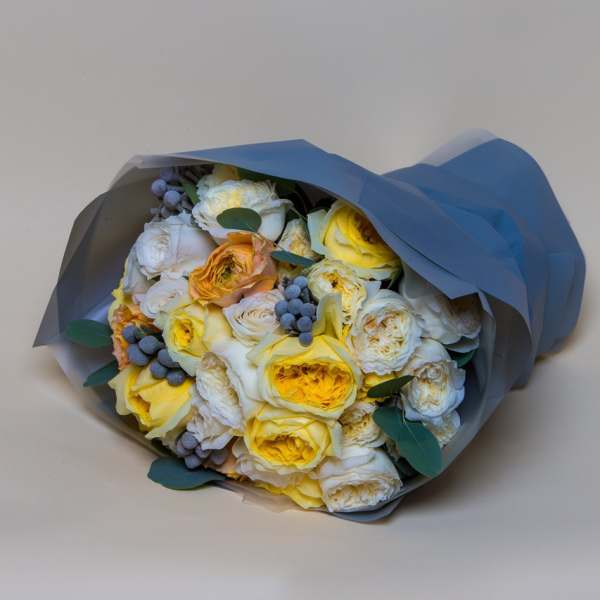 Bouquet of yellow and white roses wrapped in blue paper