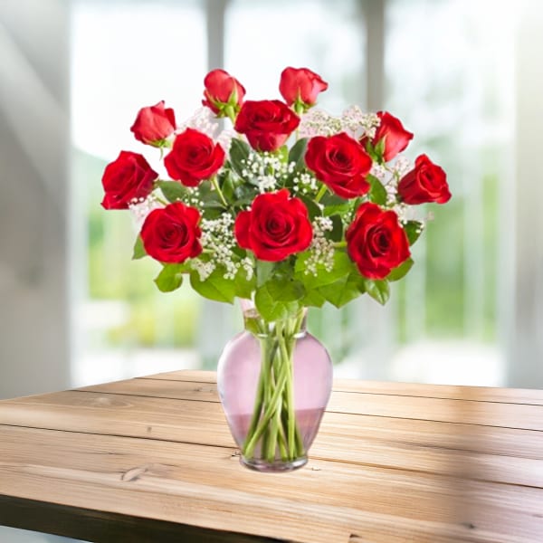 Red roses arranged in a pink glass vase
