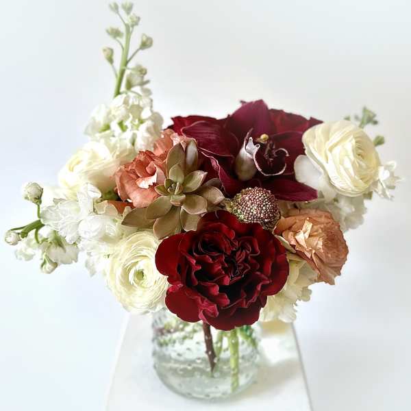 Bouquet of red, cream, and peach flowers in a clear glass vase