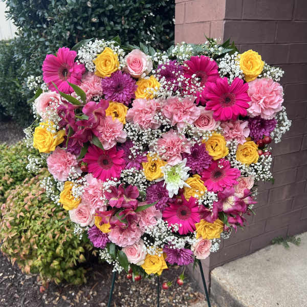 Heart-shaped floral spray with pink, yellow, and purple blooms on an easel