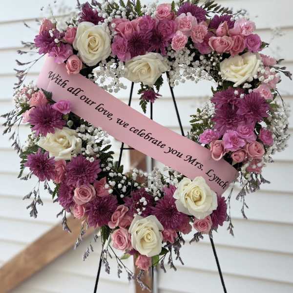 Heart-shaped floral wreath with pink and white roses on a stand
