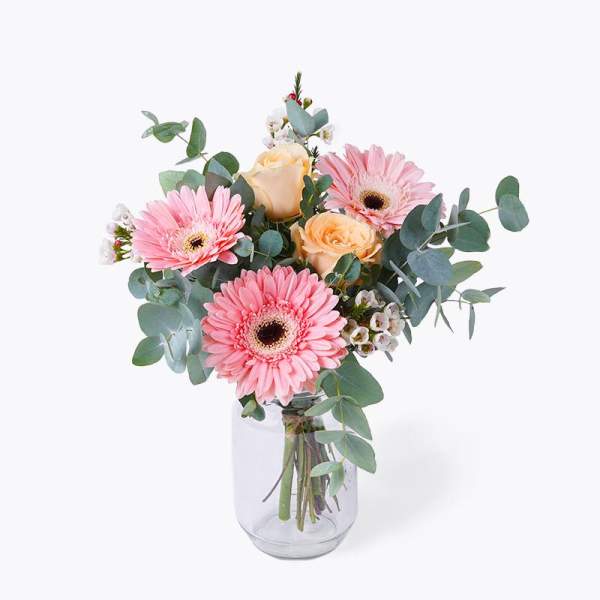 Pink gerbera daisies and peach roses in a glass vase
