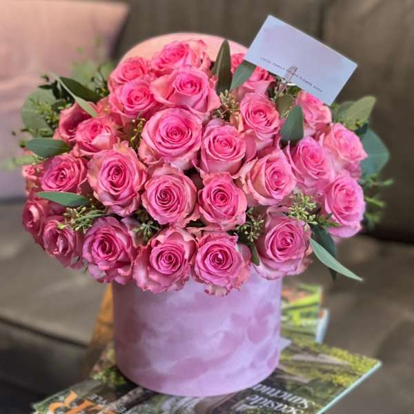 Pink roses arranged in a lavender hatbox