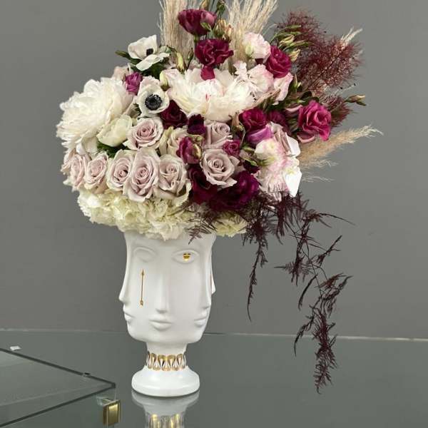 Floral arrangement in a white sculptural vase with pink and white blooms