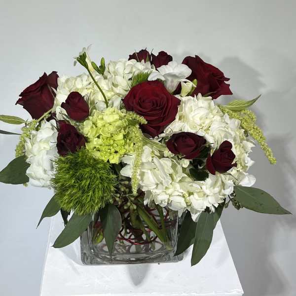 Red roses and white hydrangeas in a clear square vase