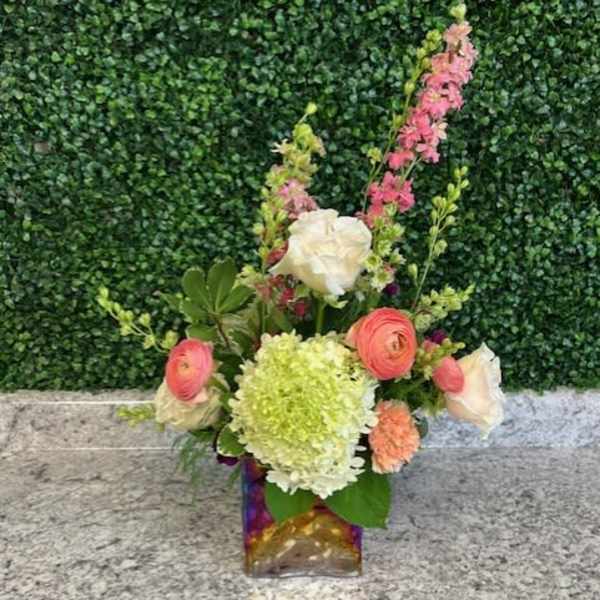 Mixed bouquet in a square glass vase with pink, white, and green blooms