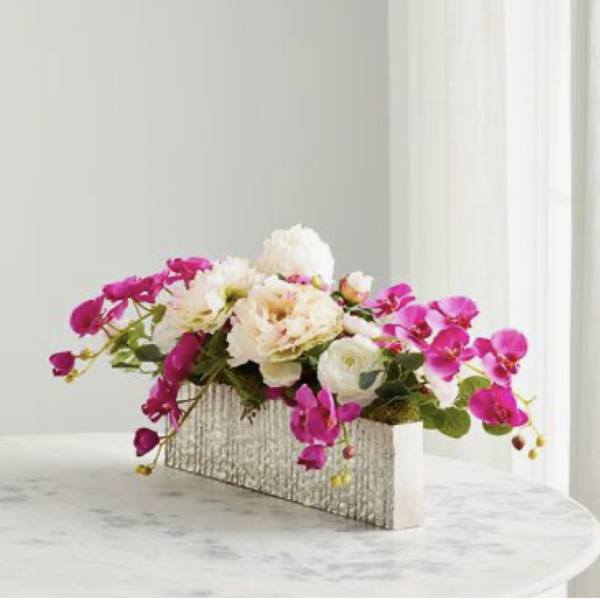 Pink orchids and white flowers in a rectangular textured vase