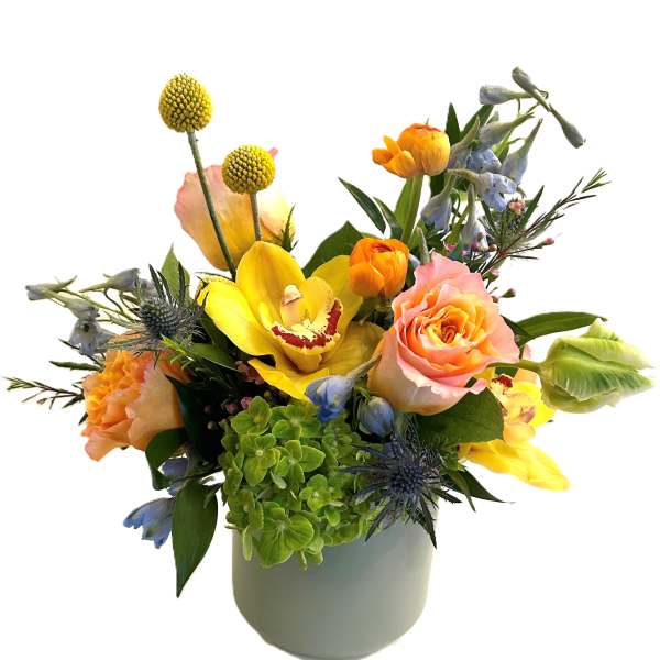 Mixed bouquet in a white vase with yellow, peach, and blue flowers
