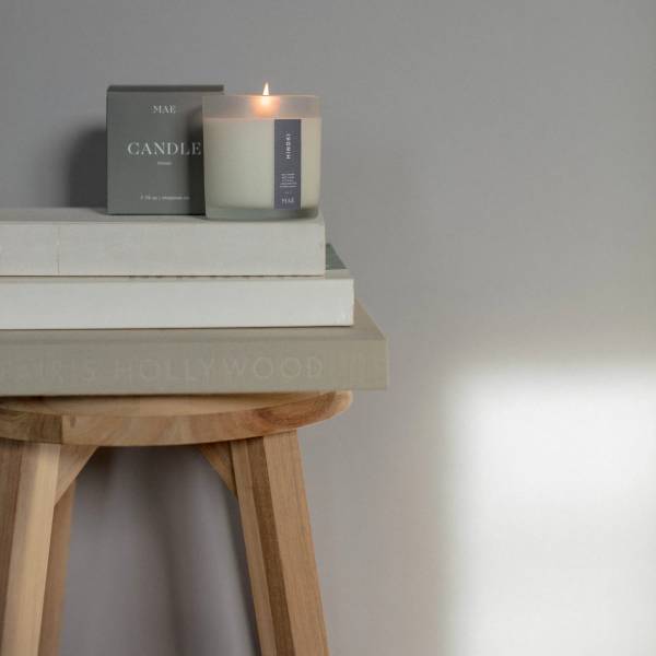 Lit candle in a glass jar beside its box on stacked books