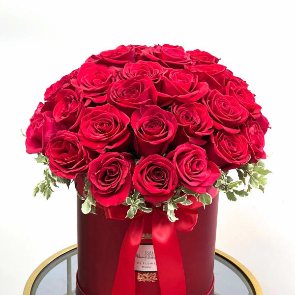 Red roses arranged in a round hat box with a ribbon