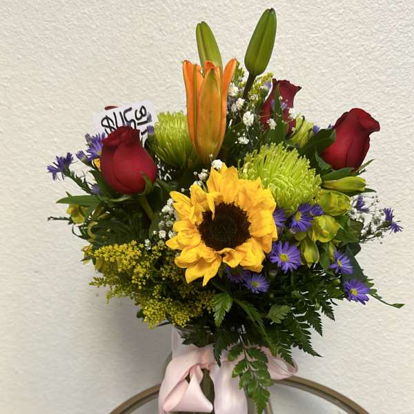 Bouquet of mixed flowers in a glass vase with a pink ribbon