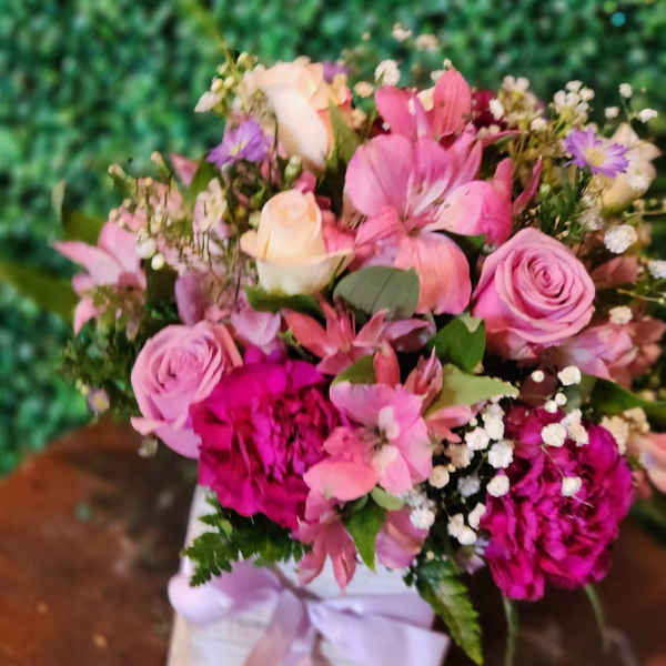 Pink and lavender mixed flower arrangement in a white box with ribbon
