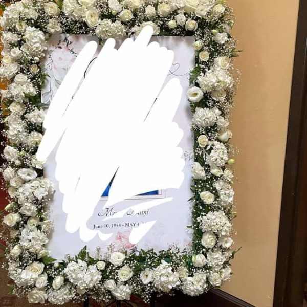 White floral funeral frame on an easel with roses and baby's breath