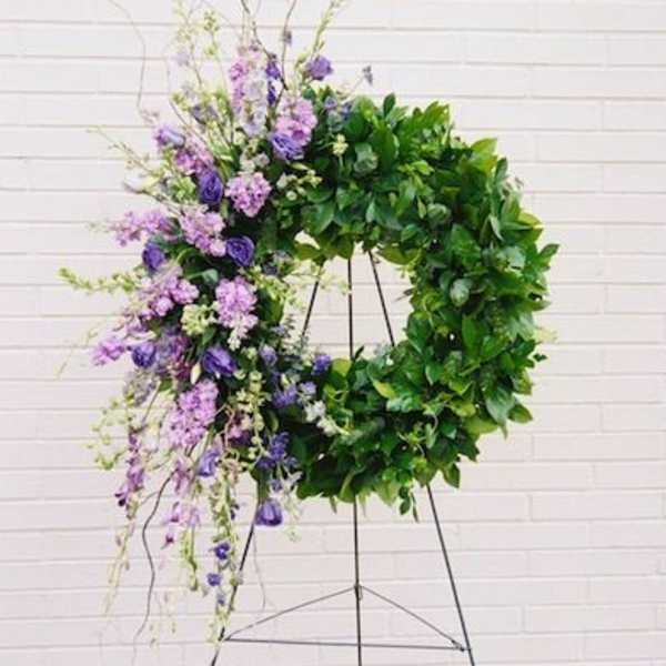 Large purple and green floral wreath on a metal stand