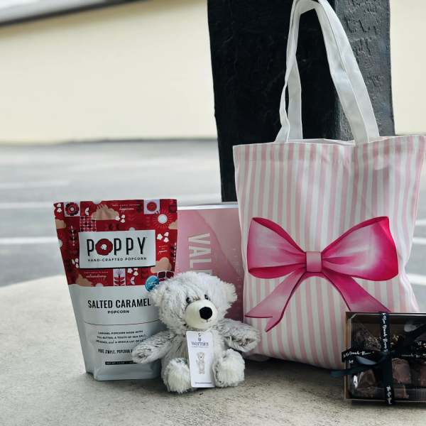 Gift bag with popcorn, teddy bear, chocolates, and a candle