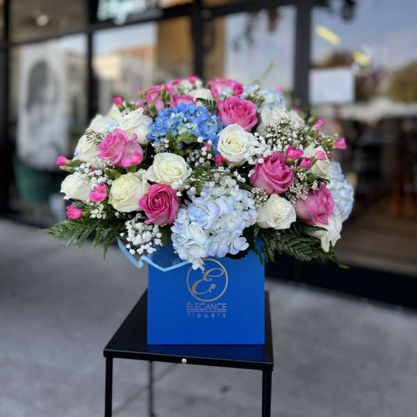Bouquet of pink and white roses with blue hydrangeas in a blue box