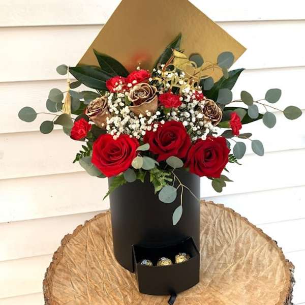 Red roses and dried roses in a black box with chocolates