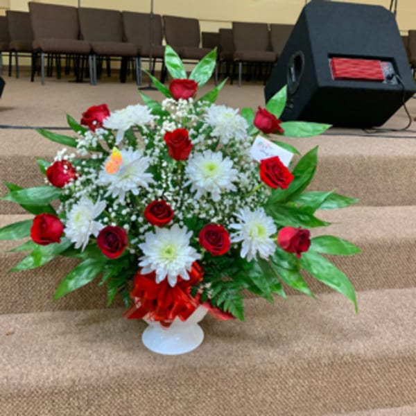 Red roses and white daisies in a white pedestal vase