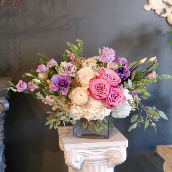 Pink and purple rose bouquet in a square glass vase