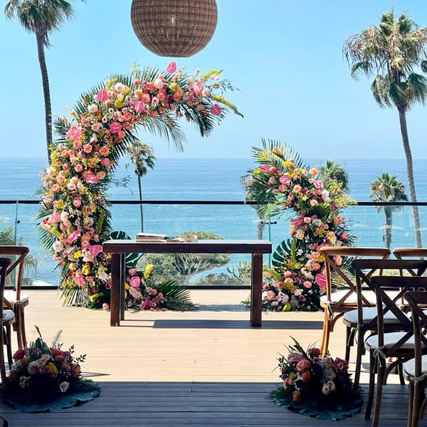 Floral wedding arch with pink and peach flowers overlooking the ocean